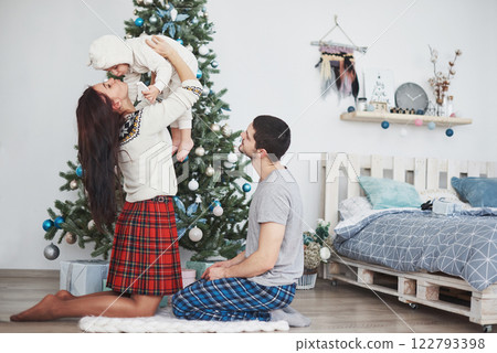 Happy family at christmas in morning opening gifts together near the fir tree. The concept of family happiness and well-being 122793398