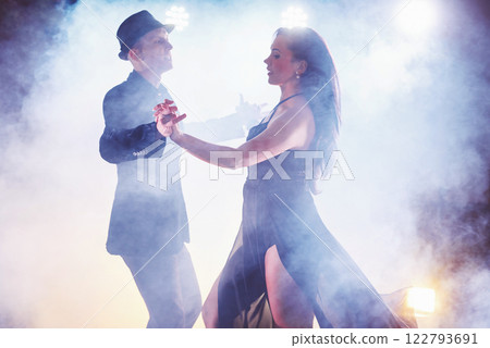 Skillful dancers performing in the dark room under the concert light and smoke. Sensual couple performing an artistic and emotional contemporary dance Skillful dancers performing in the dark room under the concert light and smoke. Sensual couple performing an artistic and emotional contemporary dance 122793691