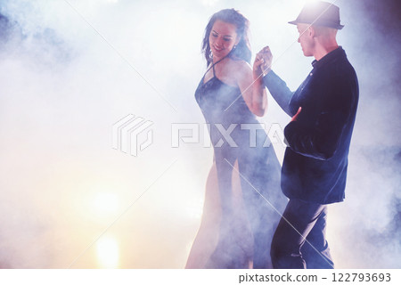 Skillful dancers performing in the dark room under the concert light and smoke. Sensual couple performing an artistic and emotional contemporary dance Skillful dancers performing in the dark room under the concert light and smoke. Sensual couple performing an artistic and emotional contemporary dance 122793693