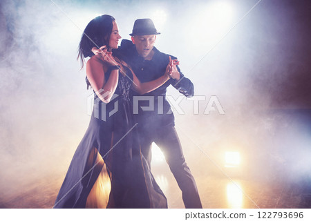 Skillful dancers performing in the dark room under the concert light and smoke. Sensual couple performing an artistic and emotional contemporary dance 122793696