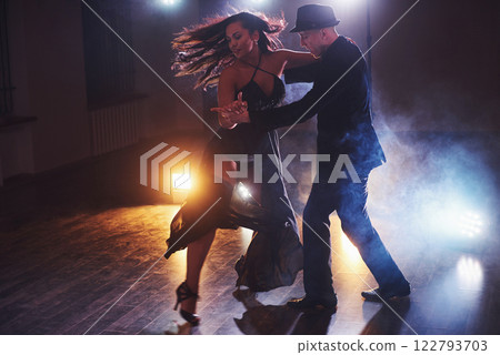 Skillful dancers performing in the dark room under the concert light and smoke. Sensual couple performing an artistic and emotional contemporary dance 122793703
