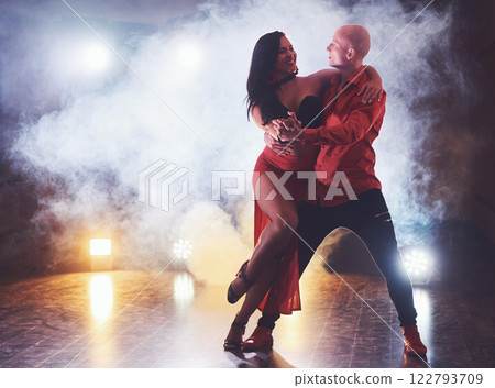 Skillful dancers performing in the dark room under the concert light and smoke. Sensual couple performing an artistic and emotional contemporary dance Skillful dancers performing in the dark room under the concert light and smoke. Sensual couple performing an artistic and emotional contemporary dance 122793709