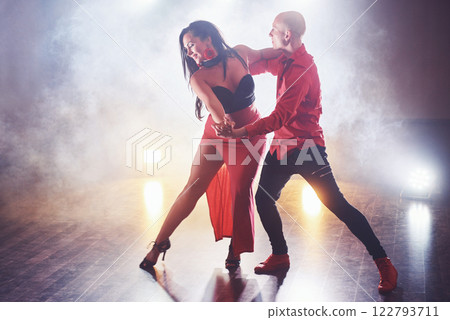 Skillful dancers performing in the dark room under the concert light and smoke. Sensual couple performing an artistic and emotional contemporary dance 122793711