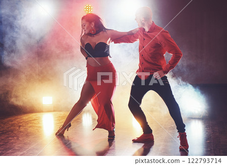 Skillful dancers performing in the dark room under the concert light and smoke. Sensual couple performing an artistic and emotional contemporary dance 122793714