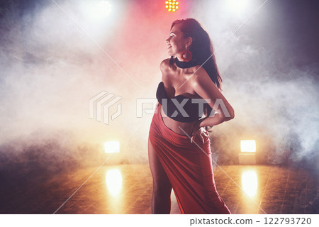 Skillful and beautiful dancer girl performing in the dark room under the concert light and smoke, performing an artistic and emotional contemporary dance 122793720
