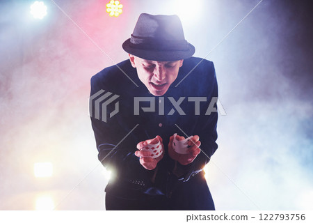 Magician showing trick with playing cards. Magic or dexterity, circus, gambling. Prestidigitator in dark room with fog 122793756