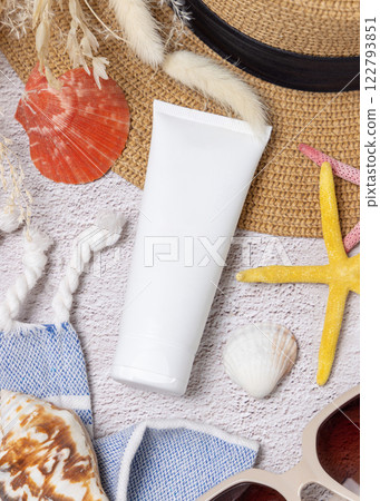 Sunscreen cream tube on hat near towel, seashells and starfishes top view, cosmetic mockup 122793851