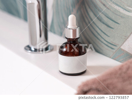 Dropper bottle with label near brown towels on basin in tropical bathroom close up, cosmetic mockup Dropper bottle with label near brown towels on basin in tropical bathroom close up, cosmetic mockup 122793857