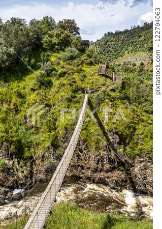 Suspension pedestrian bridge of the Barca da Amieira walkways in Amieira do Tejo, Portugal. Suspension pedestrian bridge of the Barca da Amieira walkways in Amieira do Tejo, Portugal. 122794063