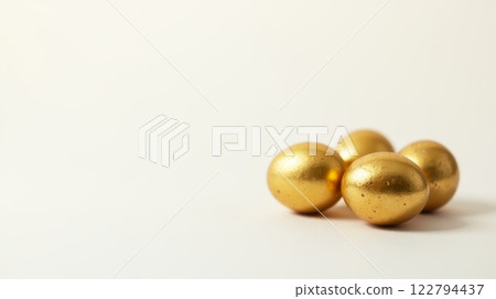 Close-up of golden eggs grouped together on a white background with copy space, symbolizing luxury, prosperity, and Easter themes 122794437
