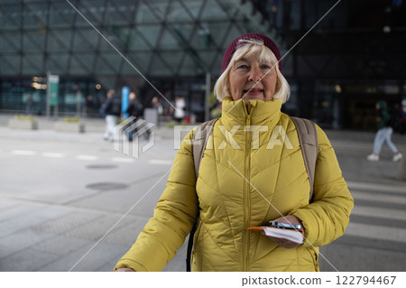 Senior female tourist in airport hold suitcase valise passport ticket schedule to check flight departure gate. Travel and tourism concept, people with backpack on shoulders. 122794467