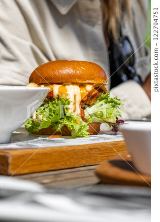 delicious burger served with fresh greens, generous amount of sauce delicious burger served with fresh greens, generous amount of sauce 122794751