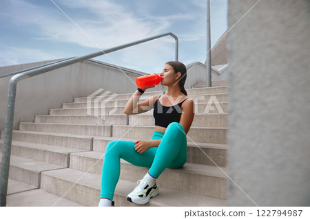 Fitness Girl Drinks Protein Shake. Sexy Woman In Fashion Sporty Outfit Has Break In Interval Exercises. Young Female Drinking Water. Outdoor Cardio Workout And Sport Nutrition. Fitness Girl Drinks Protein Shake. Sexy Woman In Fashion Sporty Outfit Has Break In Interval Exercises. Young Female Drinking Water. Outdoor Cardio Workout And Sport Nutrition. 122794987
