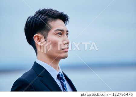A young man in a suit looking into the distance 122795476