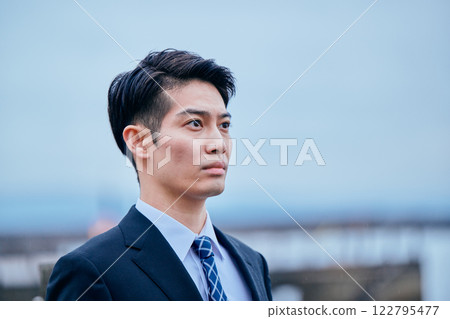 A young man in a suit looking into the distance 122795477