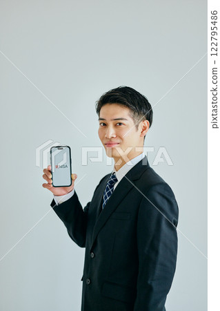 A young man in his twenties holding a smartphone A young man in his twenties holding a smartphone 122795486