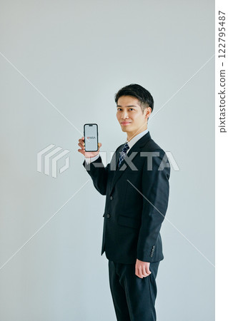 A young man in his twenties holding a smartphone A young man in his twenties holding a smartphone 122795487