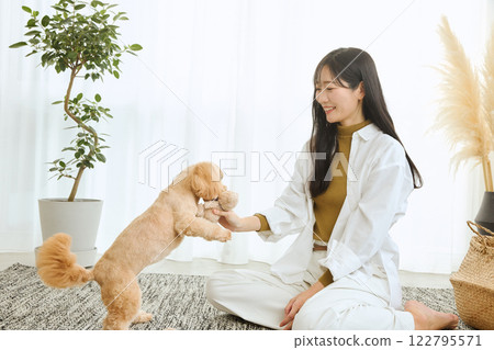 Woman playing with her dog in the living room 122795571