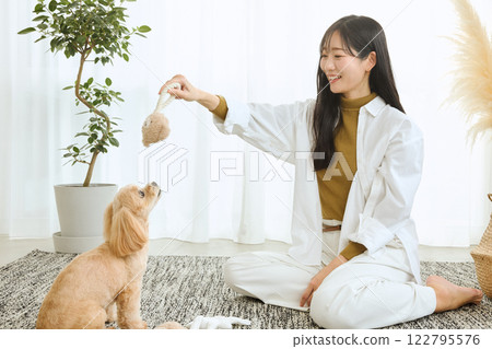 Woman playing with her dog in the living room 122795576