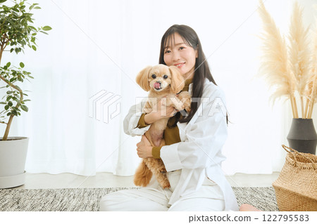 Woman playing with her dog in the living room 122795583