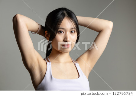 Beautiful woman in sportswear tying her hair Beautiful woman in sportswear tying her hair 122795784