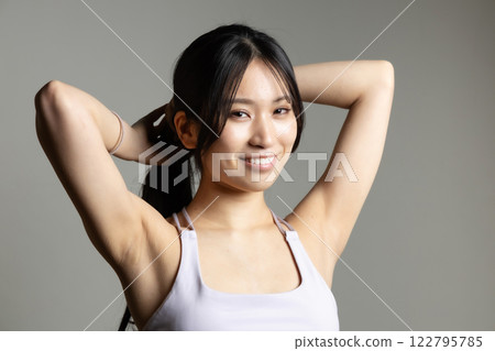 Beautiful woman in sportswear tying her hair Beautiful woman in sportswear tying her hair 122795785