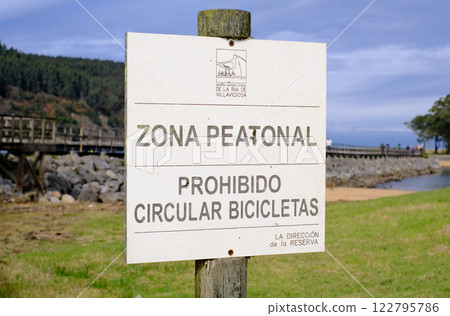 A sign on a post that says Zona Peatonal Prohibido Circular Bicicletas in Spanish 122795786