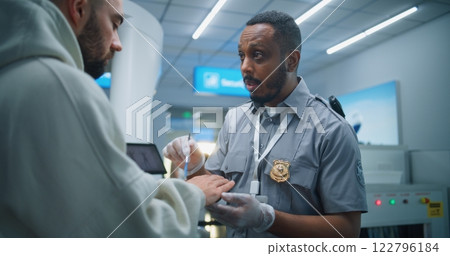 Airport Terminal: Security Officer Conducts TSA Hand Swab Screening with Brush to Adult Man 122796184