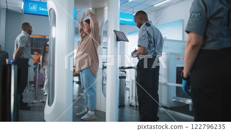 Diverse People Passing Through Metal Detector Scanner. Security Officer Checks Passengers on Tablet Diverse People Passing Through Metal Detector Scanner. Security Officer Checks Passengers on Tablet 122796235