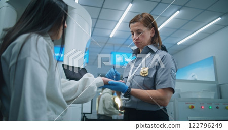 Female Security Officer Doing Doing TSA Hand Swab Screening with Brush to Woman for Plane Flight 122796249