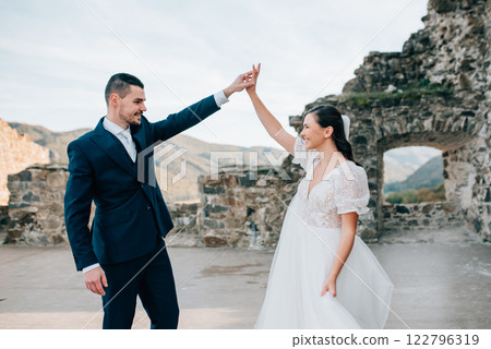 Bride and groom holding hands, looking at each other. Wedding couple standing outside near ruins. Bride and groom holding hands, looking at each other. Wedding couple standing outside near ruins. 122796319