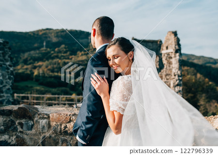 Portrait of beautiful wedding couple standing outside near ruins. 122796339