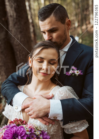 Portrait of beautiful bride and an elegant groom in nature, surrounded by a forest. 122796365