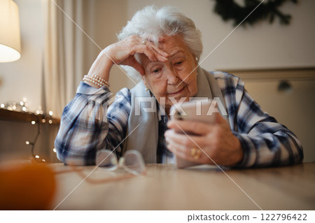 Elderly woman struggling to use smartphone, looking confused. Elderly woman struggling to use smartphone, looking confused. 122796422