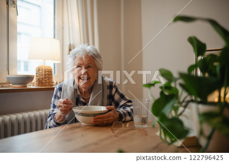 Poor elderly woman eating soup at the dining table. 122796425