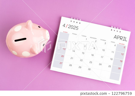 Desk calendar for April 2025 and pink piggy bank on purple background. Desk calendar for April 2025 and pink piggy bank on purple background. 122796759