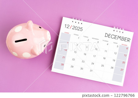 Desk calendar for December 2025 and pink piggy bank on purple background. Desk calendar for December 2025 and pink piggy bank on purple background. 122796766