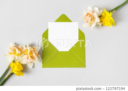 Green envelope with clean white sheet of paper for your text and spring flowers white tulips and daffodils on gray background. Invitation to the holidays. Hello spring Green envelope with clean white sheet of paper for your text and spring flowers white tulips and daffodils on gray background. Invitation to the holidays. Hello spring 122797194