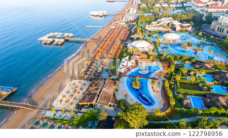 Aerial view of a beachfront luxury resort with pools, a water park, and private cabanas Aerial view of a beachfront luxury resort with pools, a water park, and private cabanas 122798956