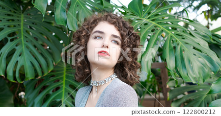 Woman with curly hair is wearing a necklace and a red lipstick 122800212