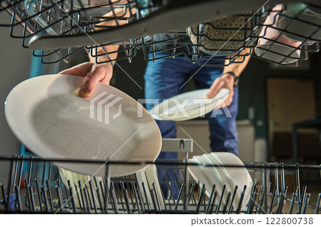 Man loading plates into dishwasher in kitchen Man loading plates into dishwasher in kitchen 122800738