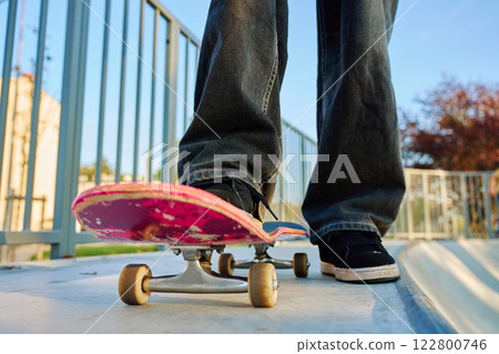 Skateboarder riding on pink skateboard at skatepark 122800746