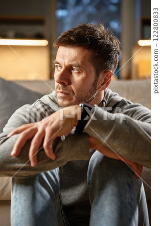 Thoughtful man sitting alone at home Thoughtful man sitting alone at home 122800833