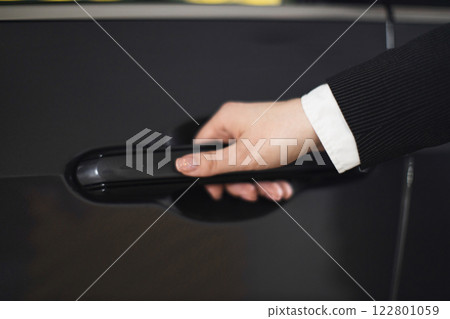 Caucasian adult female hand in business attire opening black car door, symbolizing professionalism and travel. Caucasian adult female hand in business attire opening black car door, symbolizing professionalism and travel. 122801059