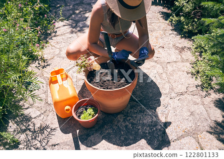 An unrecognizable woman reads how to transplant plants correctly on her smartphone. The brunette is going to transplant plants into a clay pot. High quality photo 122801133