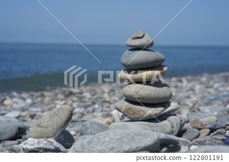 Balancing rocks on a pebble beach during sunset. Smooth pebbles on the beach against the background of the sea and sunlight, creating a side effect on the water. High quality photo Balancing rocks on a pebble beach during sunset. Smooth pebbles on the beach against the background of the sea and sunlight, creating a side effect on the water. High quality photo 122801191