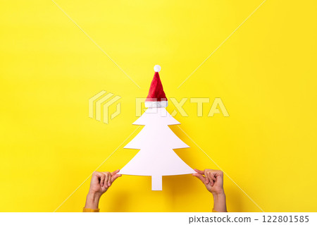 A Christmas tree in hand on a yellow background. A Christmas tree in hand on a yellow background. 122801585