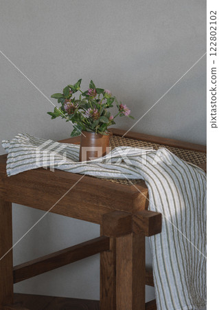 wild clover in ceramic jug on rattan stool as decoration element. Kitchen aesthetics concept 122802102
