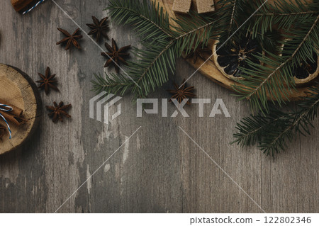 Beautiful Christmas atmospheric flat lay. Spruce twigs, star anise, dried orange slices, brown sugar and round cutting board on a wooden background, copy space. Beautiful Christmas atmospheric flat lay. Spruce twigs, star anise, dried orange slices, brown sugar and round cutting board on a wooden background, copy space. 122802346