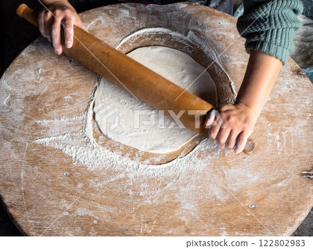 above view of woman rolls out dough on low table 122802983
